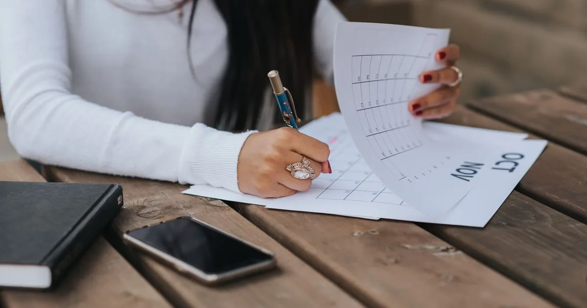 Hands making a date note in a planner