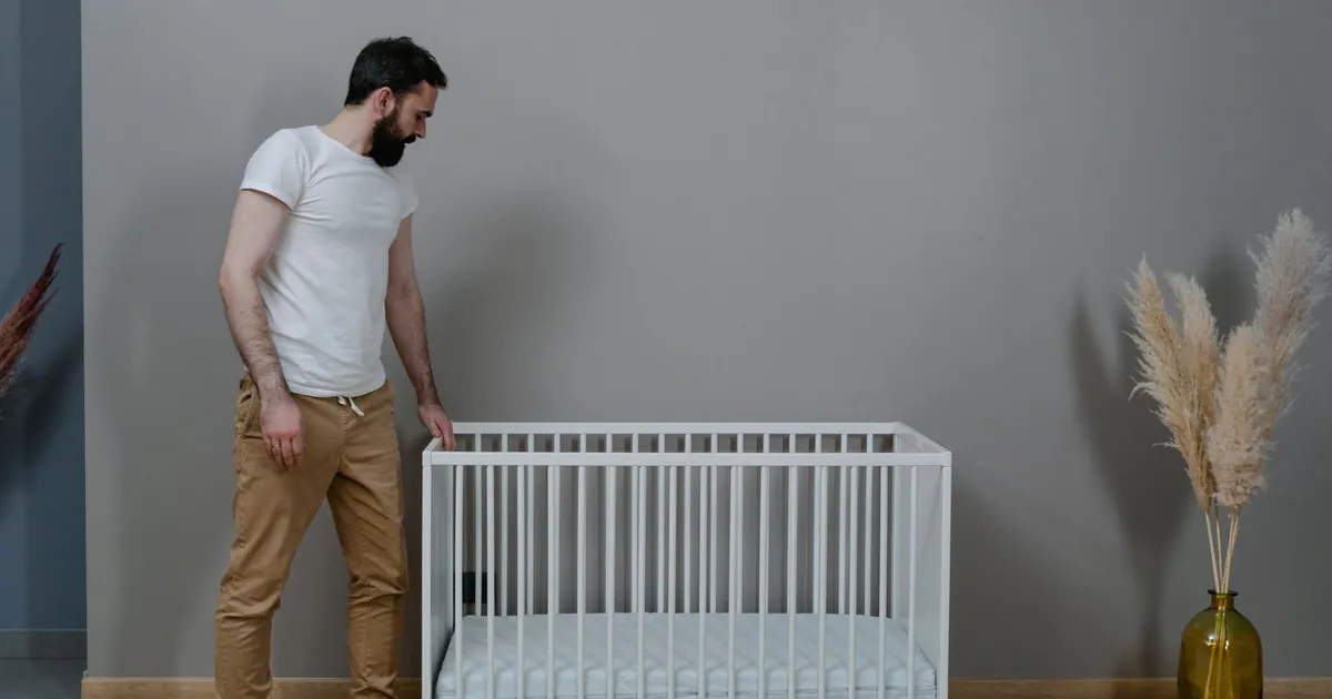 İçinde oyuncak veya yastık olmayan bir beşiğin yanındaki yetişkin