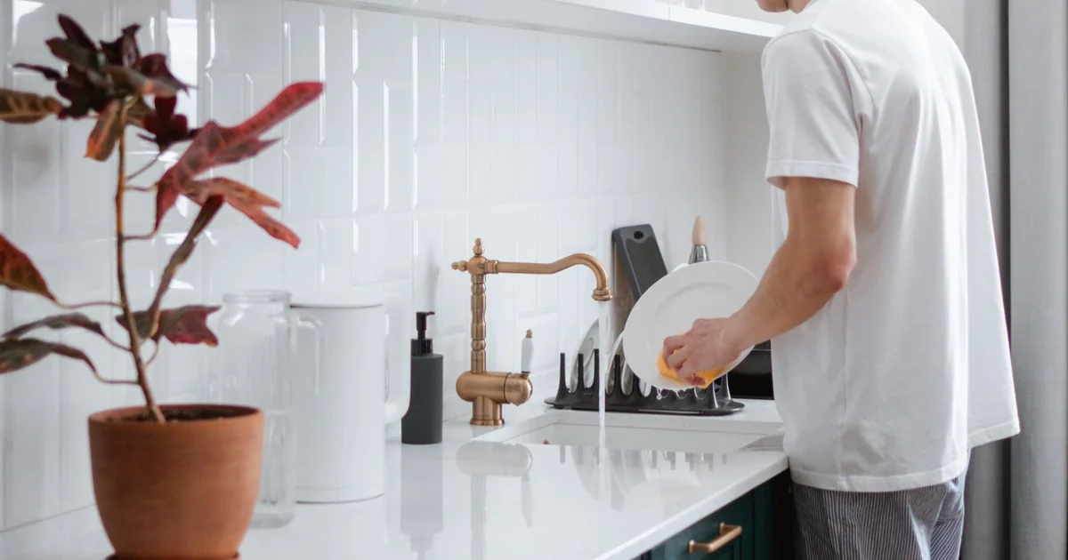 A person washing dishes at a kitchen sink