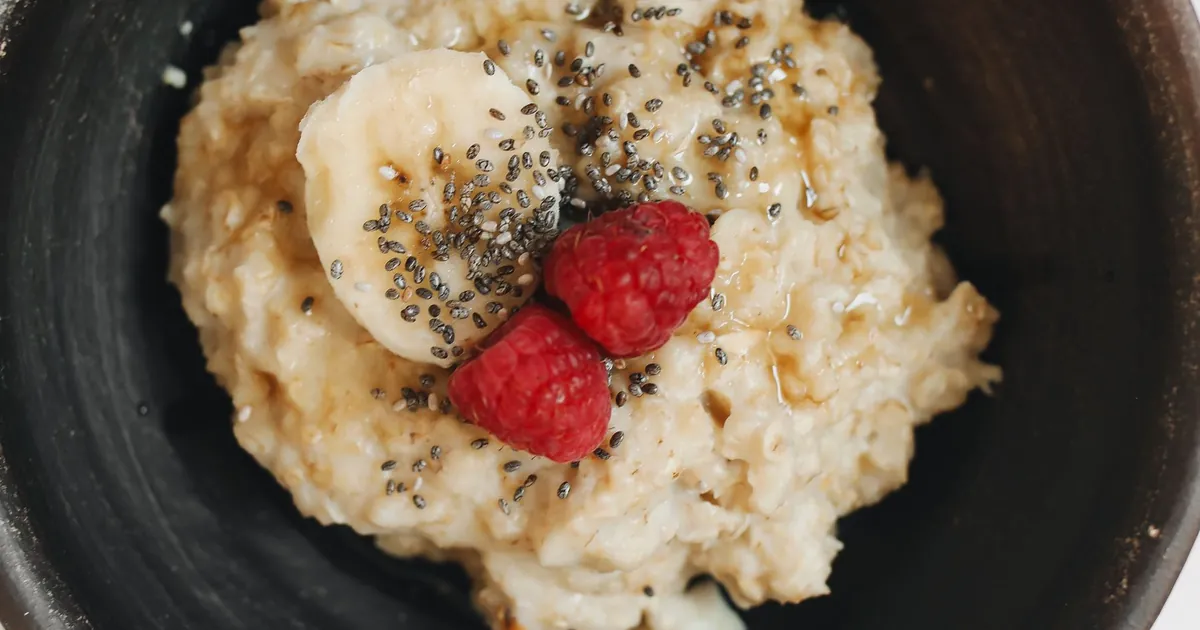 A bowl of oats topped with banana and raspberries