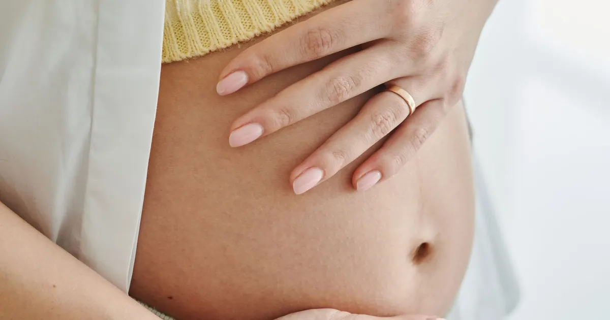 Hands resting on a pregnant person’s belly