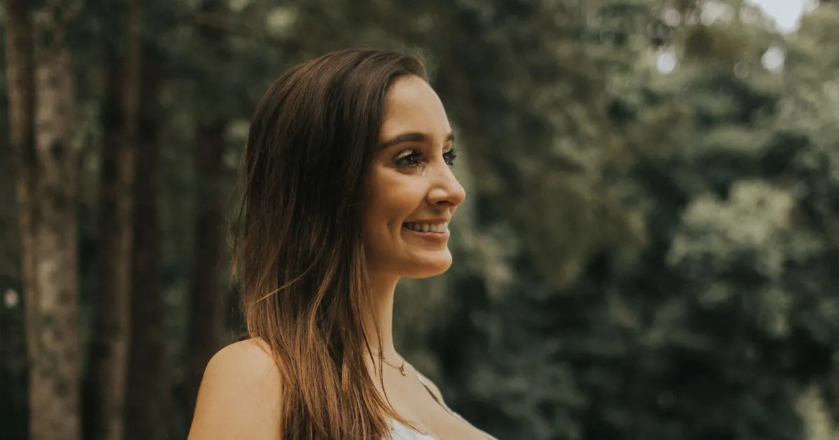 A pregnant person in a white dress in a park